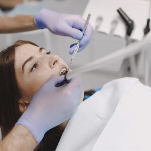 Female patient sitting in the dental chair while dentist doing e Root canal Treatment