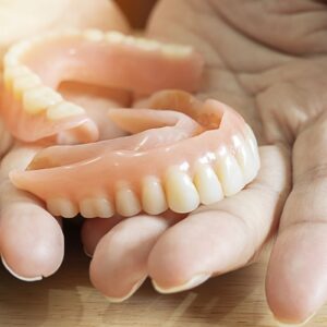 Close up of female hands holding flexible nylon denture. Denture